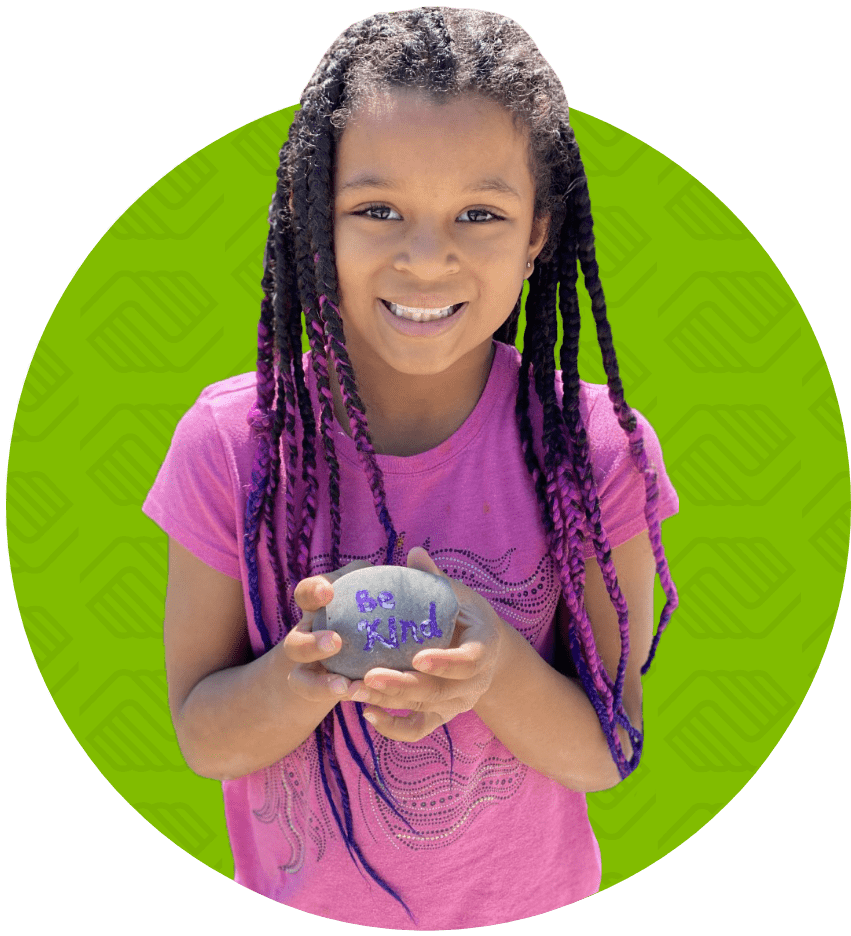 girl holding a rock that says be kind
