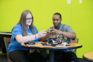 girl and mentor building robot